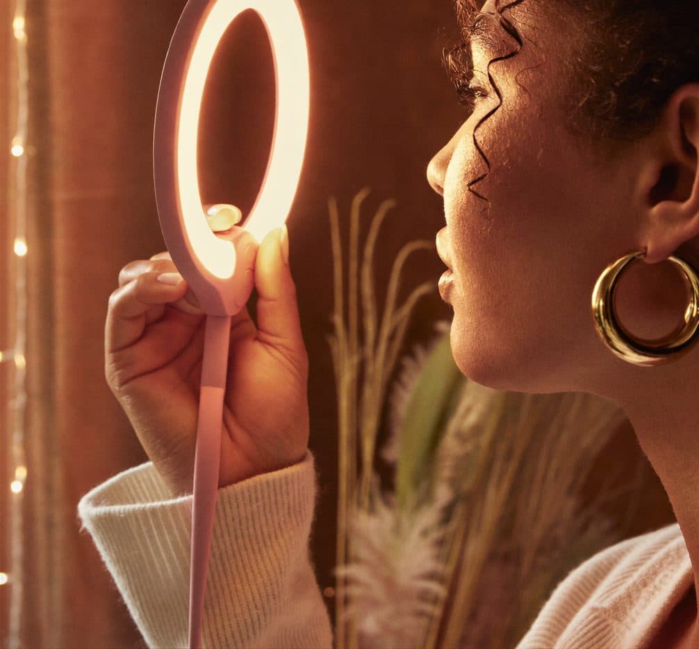 Vue du dessus : ring light circulaire et smartphone vertical sur trépied, marbre crème — setup créateur minimaliste